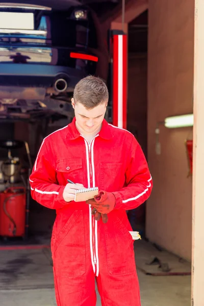 Male auto mechanic standing making notes — Stock Photo, Image