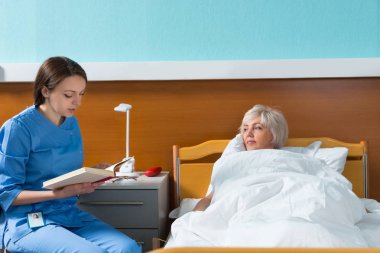 Üniformalı genç çekici hemşire onun pati için bir kitap okuyor