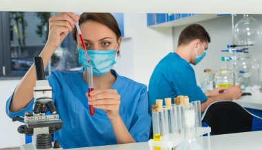 Tek tip bir maske takarak içinde genç kadın bilim adamı bir pi ile doldurur