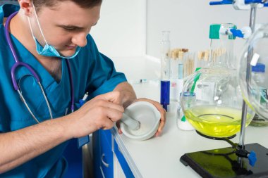 Ce üzerinde toz hazırlama bir maske takarak üniformalı genç bilim adamı