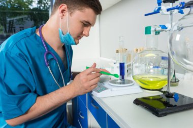 Tek tip bir maske takarak içinde erkek bilim adamı toz specia üzerinde ağırlığında.