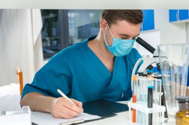 Üniformalı erkek bilim adamı bir mikroskop ve gitmek arıyor