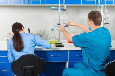 Arkadan erkek ve kadın bilim adamları bazı r yapma üniformalı görünüşü