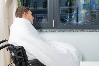 Pencerenin tekerlekli sandalye üzerinde oturan erkek hasta hasta zekâ kaplı