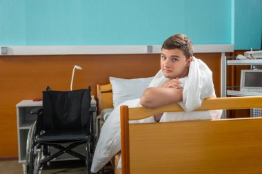 Genç hasta hasta hastane karyola üzerinde eğilerek kaplı 