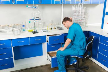 Genç asistan bir laboratuvarda bir durumda bir şey arıyor