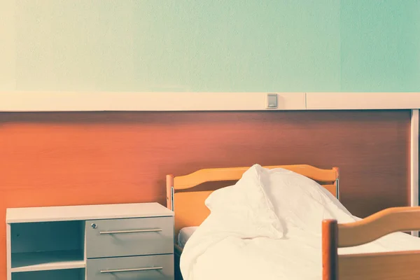 Una mesita de noche está cerca de la cama vacía del hospital —  Fotos de Stock