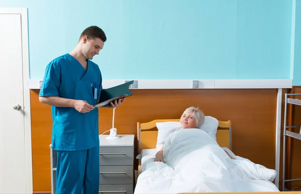 Male doctor looks at the analysis scores of his female patient — Stock Photo, Image