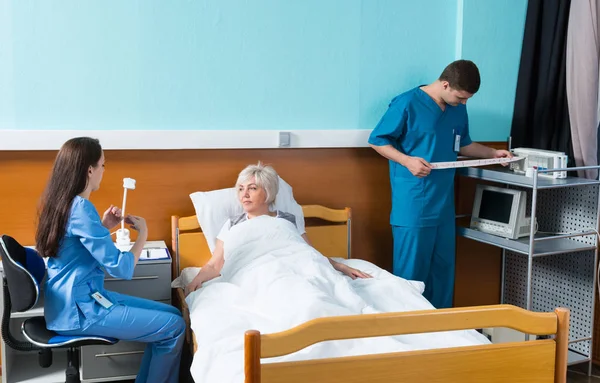 Hemşire ve doktor bir hastane yatağında bir hasta üzerinde deneylerini — Stok fotoğraf