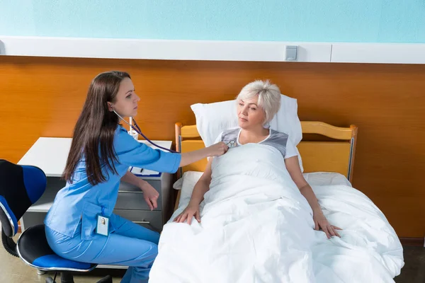 Jeune femme médecin en uniforme avec phonendoscope à l'écoute d'un — Photo