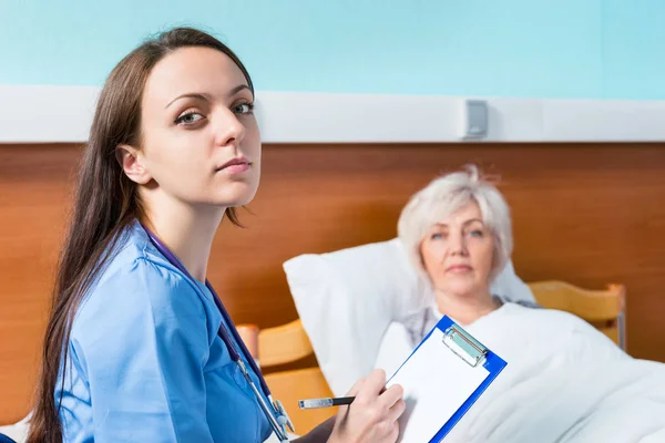Portrait of attractive female doctor writing down complaints of — Stock Photo, Image