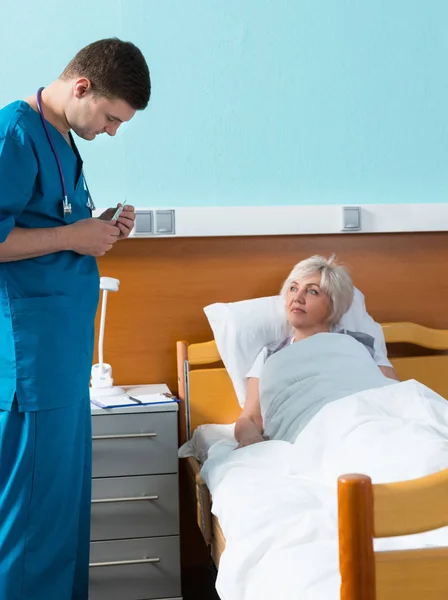 Joven guapo médico varón en uniforme con fonendoscopio en su —  Fotos de Stock