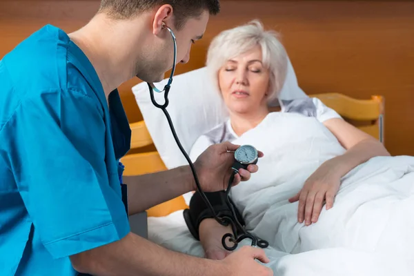 Medico in uniforme con fonendoscopio sta misurando la p arteriosa — Foto Stock