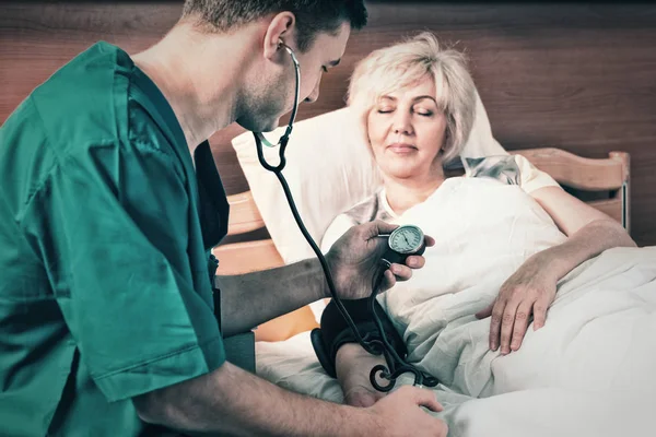 Erkek doktor phonendoscope ile üniformalı kapılarını ölçme