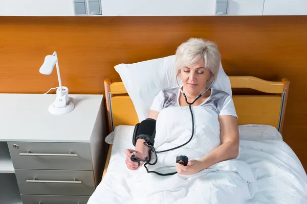 O paciente está medindo a pressão arterial usando um equipamento médico — Fotografia de Stock