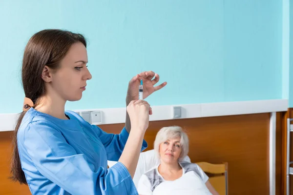 Kvinnliga läkare i uniform är redo att göra en injektion för att — Stockfoto