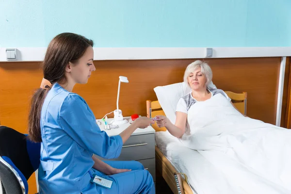 Genç doktor veya hemşire üniforması giyen hapları onun hastaya veriyor