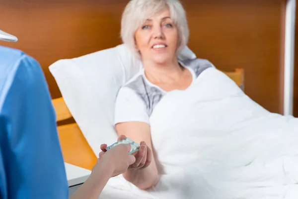 La mano del medico femminile sta dando pillole al suo paziente sorridente — Foto Stock