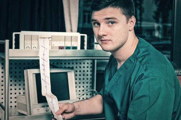 Male doctor in uniform is holding analysis of electrocardiograph — Stock Photo, Image