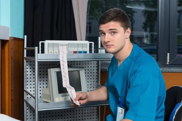 Médico en uniforme está sosteniendo el análisis del examen electrocardiográfico —  Fotos de Stock