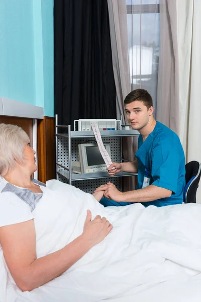 Male doctor in uniform is holding analysis of electrocardiograph — Stock Photo, Image