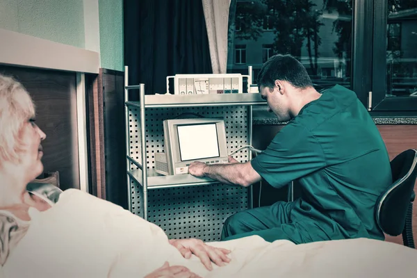 Dottore in uniforme sta guardando il monitor del dispositivo medico mentre — Foto Stock