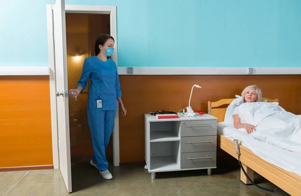 Enfermera joven en uniforme y con una máscara entró en la sala — Foto de Stock