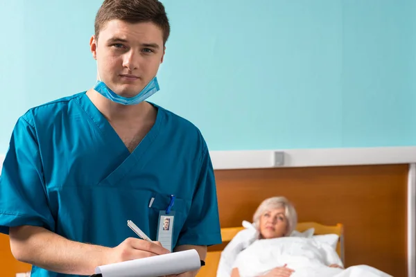 Ritratto di giovane medico maschio in uniforme che indossa una maschera che fa s — Foto Stock