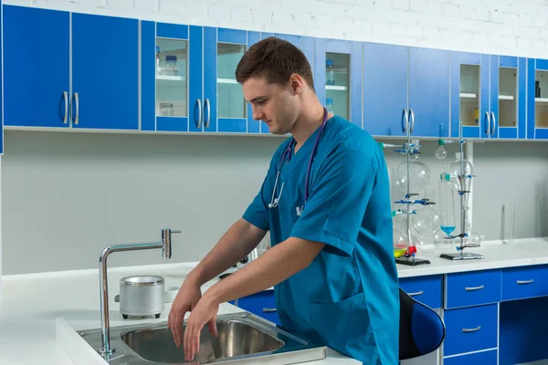 Arzt in Uniform wäscht sich im modernen Labor die Hände — Stockfoto