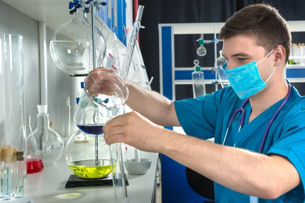 Jeune homme scientifique en uniforme portant un masque tient le test g — Photo