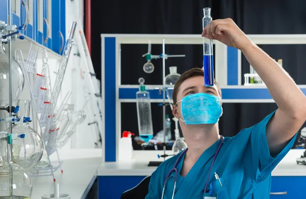 Wissenschaftler in Uniform mit Maske hält einen großen Test ab. — Stockfoto