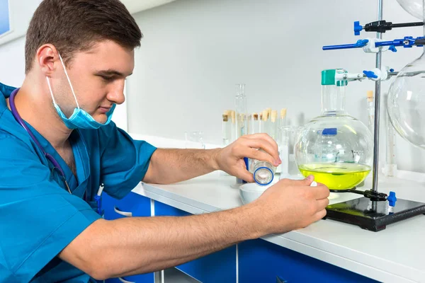 Young male scientist in uniform wearing a mask is working with c — Stock Photo, Image