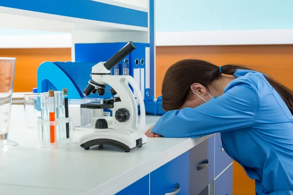 Tired female scientist in uniform is sleaping near her workplace — Stock Photo, Image