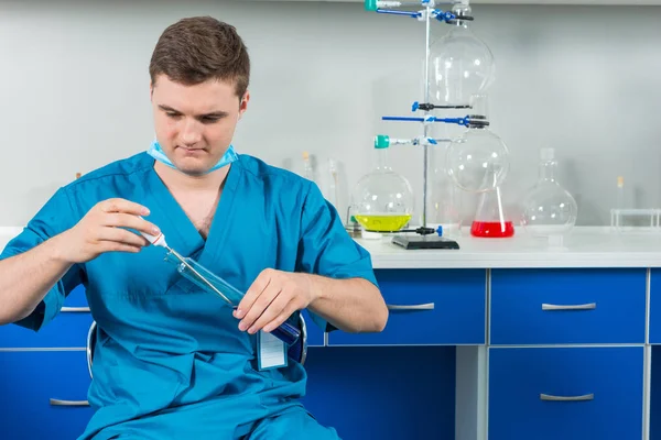 Junger männlicher Wissenschaftler in Uniform mit Maske misst das Temperat — Stockfoto