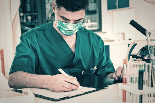 Erkek bilim adamı üniformalı ve maskeli notları yazma