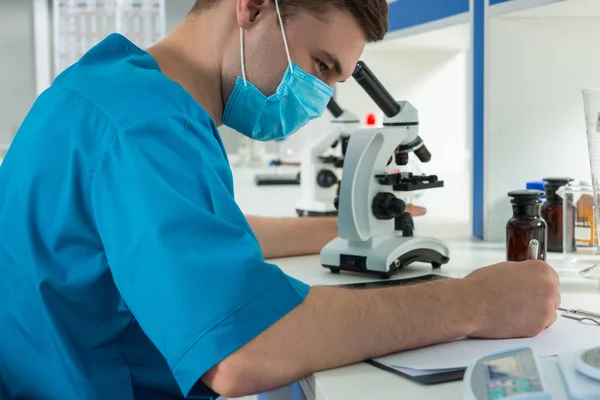 Wissenschaftler in Uniform notiert Notizen seiner Forschungen nach — Stockfoto