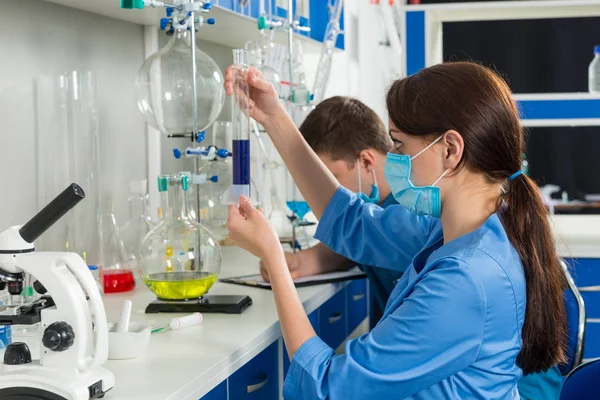 Junge Wissenschaftler in Uniform forschen im Labor — Stockfoto
