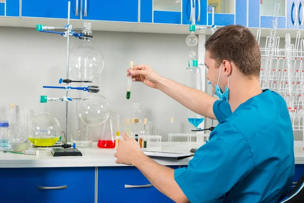 Back view of male scientist in uniform making some research in a — Stock Photo, Image
