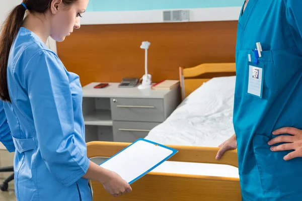 Medico donna in uniforme in possesso di un blocco a molla mentre in piedi in t — Foto Stock