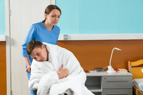 Krankenschwester in Uniform zieht Rollstuhl mit kranker Patientin — Stockfoto