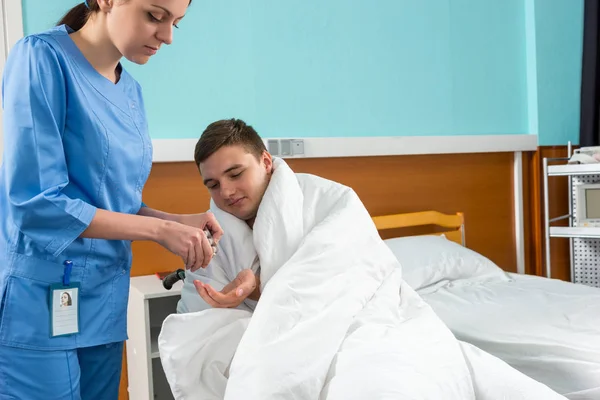 Atrakcyjnej pielęgniarki dając pigułki, aby chory pacjent siedzi na wheelcha — Zdjęcie stockowe