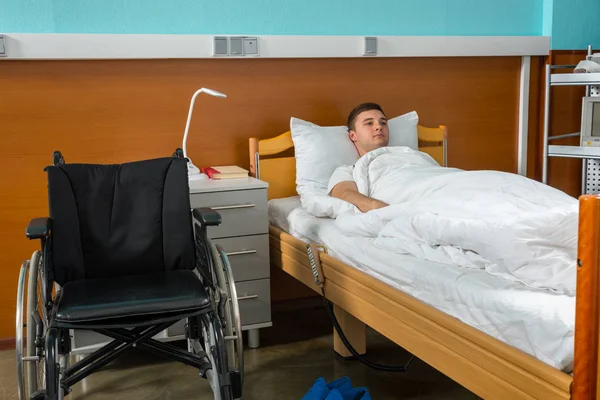 Młodych smutny mężczyzna chory pacjent leży w szpitalnym łóżku objęte wit — Zdjęcie stockowe