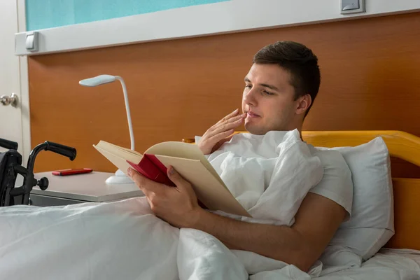 Portret van de jonge ziek mannelijke patiënt in het ziekenhuisbed liggen en — Stockfoto