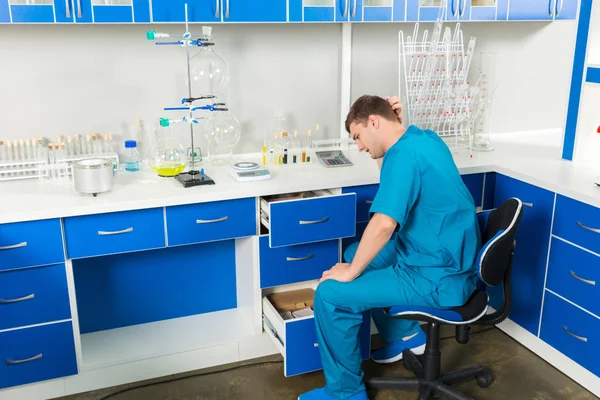 Young lab assistant is looking for something in a cases in a lab — Stock Photo, Image