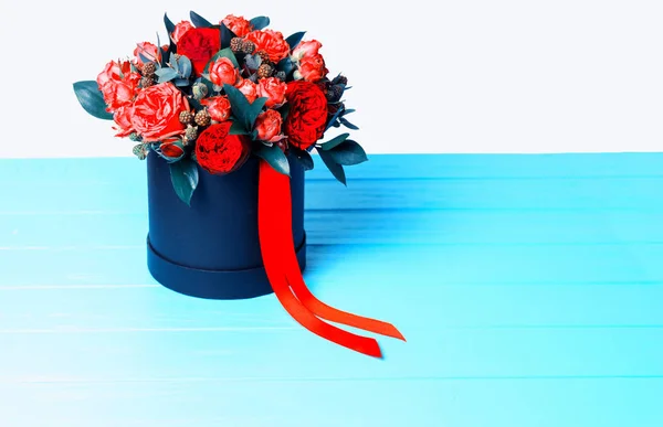 Kytice červených růží a červenou stužkou v kruhové černé skříňky — Stock fotografie