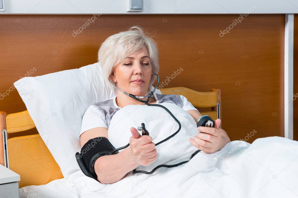 Female patient is measuring the arterial pressure using a medica