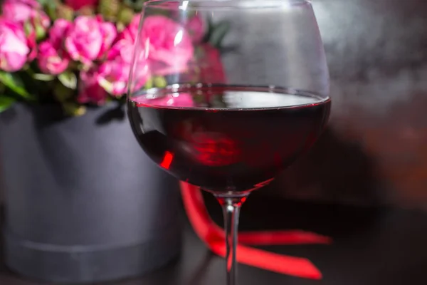 Close up of a glass with wine near stylish bouquet of pink and r — Stock Photo, Image
