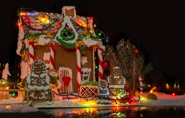 Jolie famille de pain d'épice près de la grande maison couverte de neige gingerbre — Photo