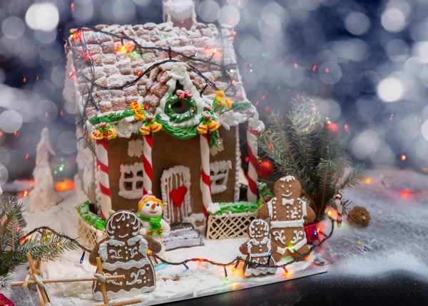 Söta pepparkakor familj nära stora snötäckta pepparkakshus — Stockfoto