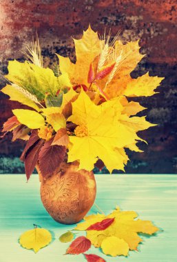 Kil sürahisi ile sonbahar yaprakları ve buğday mavi ahşap masa